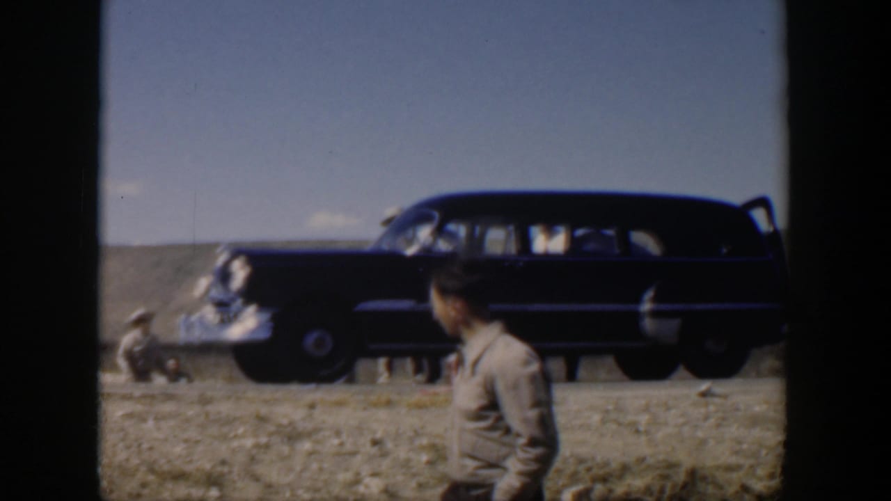 Texas 1951 roadside frame with a dark station wagon, damaged car, and a man in a tan shirt watching the scene.