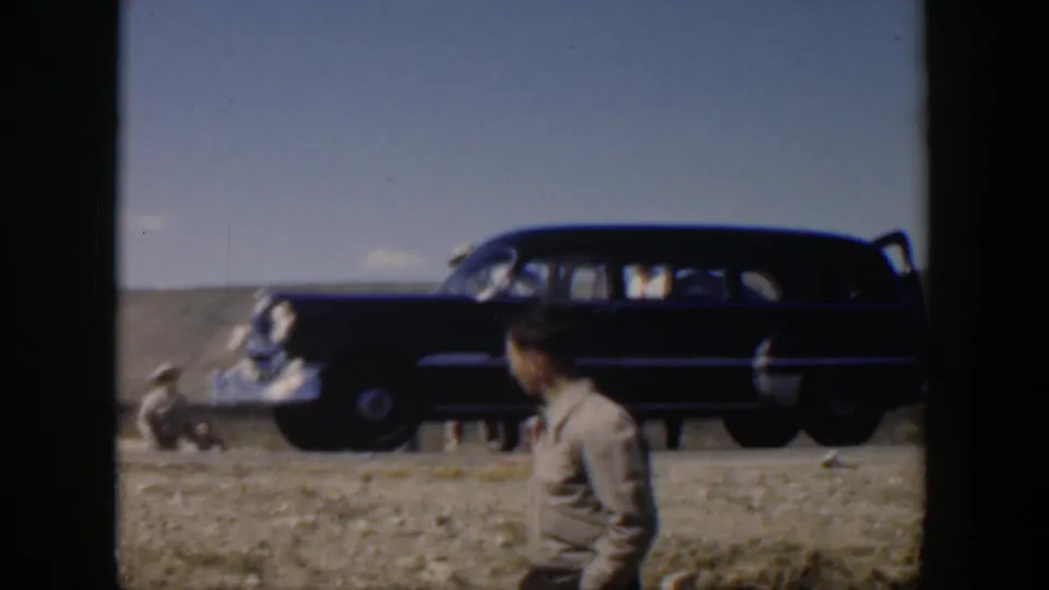 Texas 1951 roadside frame with a dark station wagon, damaged car, and a man in a tan shirt watching the scene.