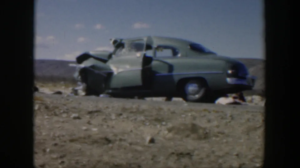 Closer 1951 Texas frame of the light green car with severe front-end damage and open doors after the collision.
