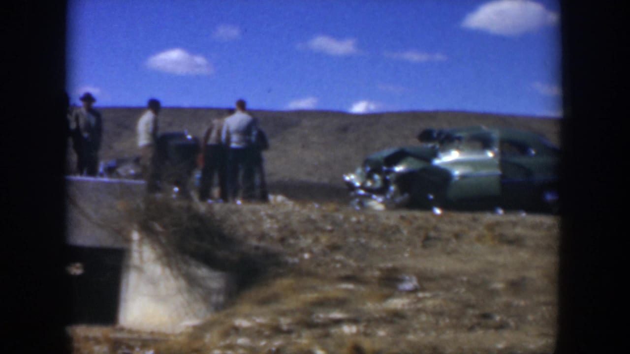 1951 Texas roadside view with adult men beside a damaged green car under a bright blue sky.