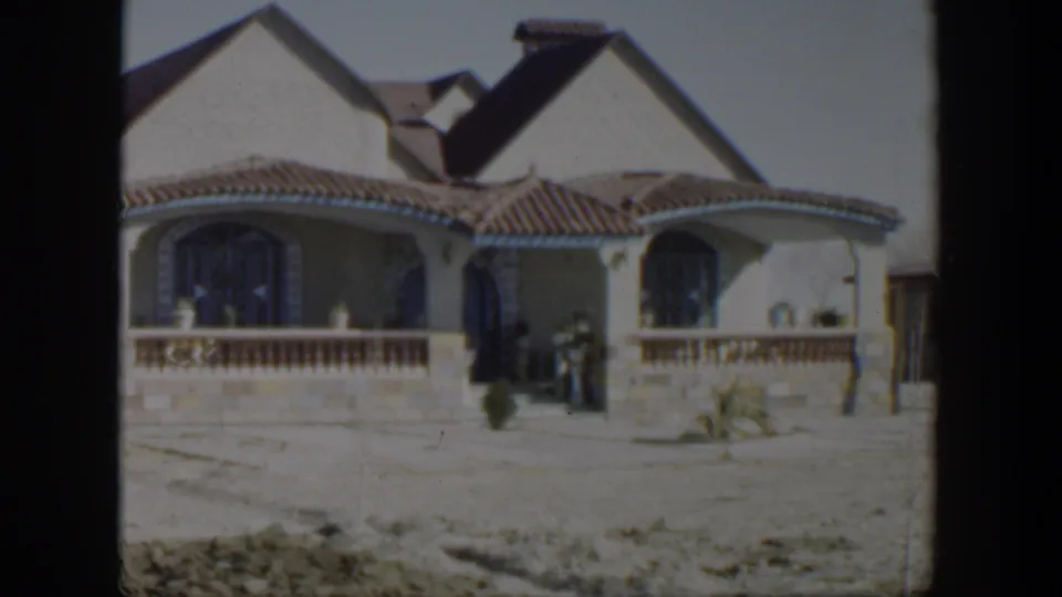 1951 Texas home-movie view of the house front, with a small figure near the entry and sparse landscaping in the dry yard.