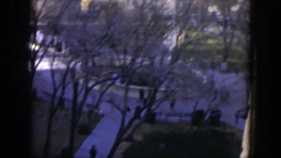 1951 Texas 8mm frame with an elevated view over intersecting courtyard paths, wintery trees, white stonework, and small walking figures.