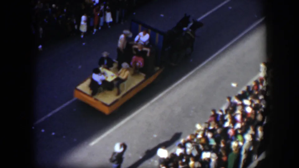 1951 Texas 8mm view of a horse-drawn parade platform moving past a packed sidewalk crowd.