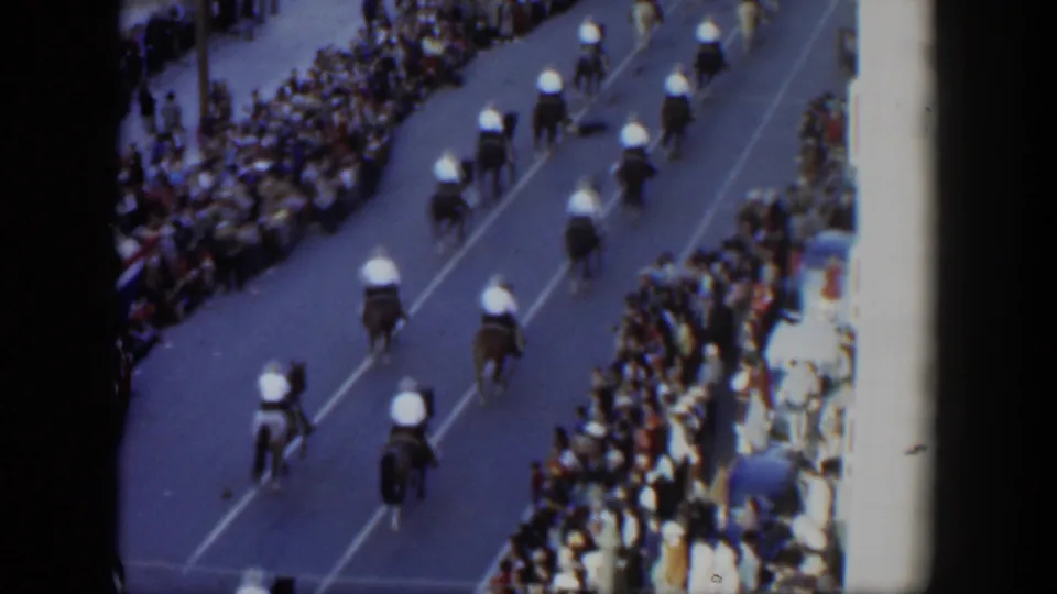 Mounted parade riders advance along a Texas street in 1951, viewed from above with spectators clustered at the curb.