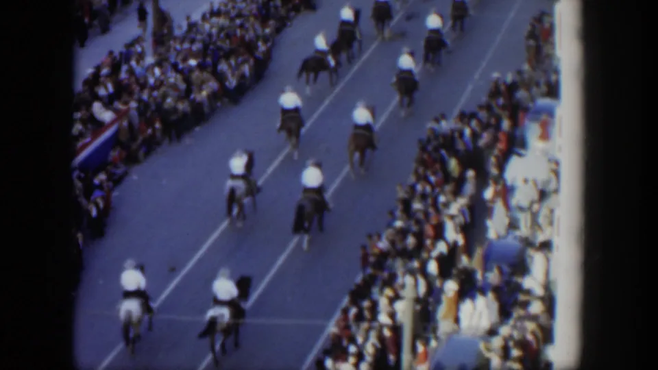 1951 Texas parade footage shows riders on horses moving away from an elevated camera as spectators watch from both sides.