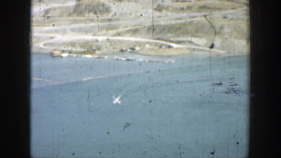 1937 California 8mm view of blue reservoir water, dry hills, and a distant road or shoreline seen through worn film texture.