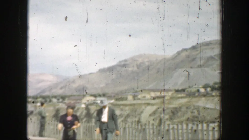 1937 California frame showing two adults receding near a fence line in a broad arid landscape.