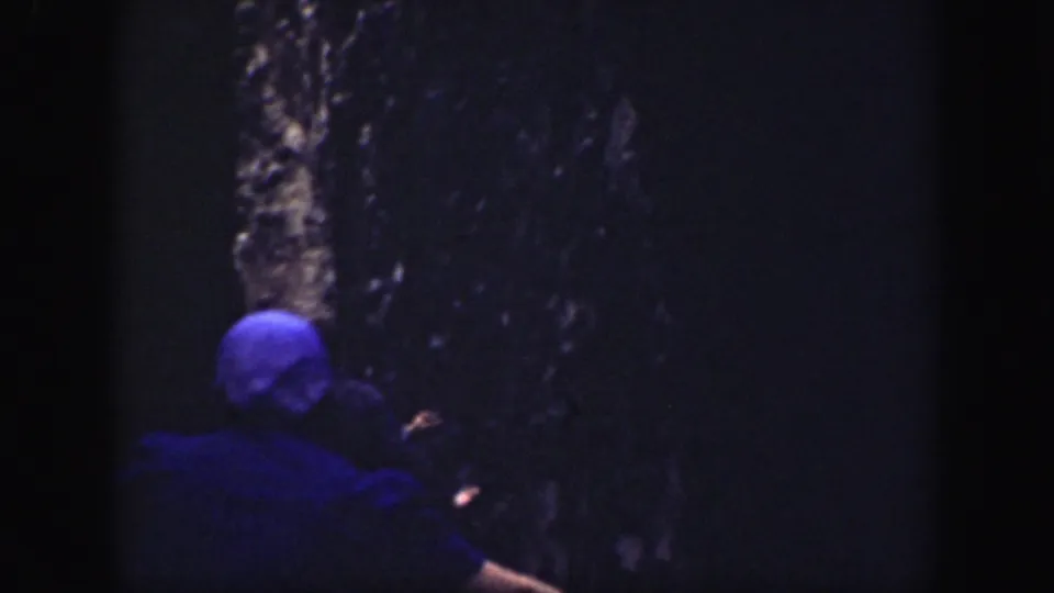 1937 California home-movie frame showing tourists in shadowed canyon walls, including a blue-capped figure seen from behind.