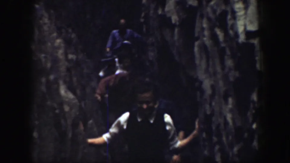 Tourists appear between steep rock walls in California, with a man near the front partly facing the 8mm camera.