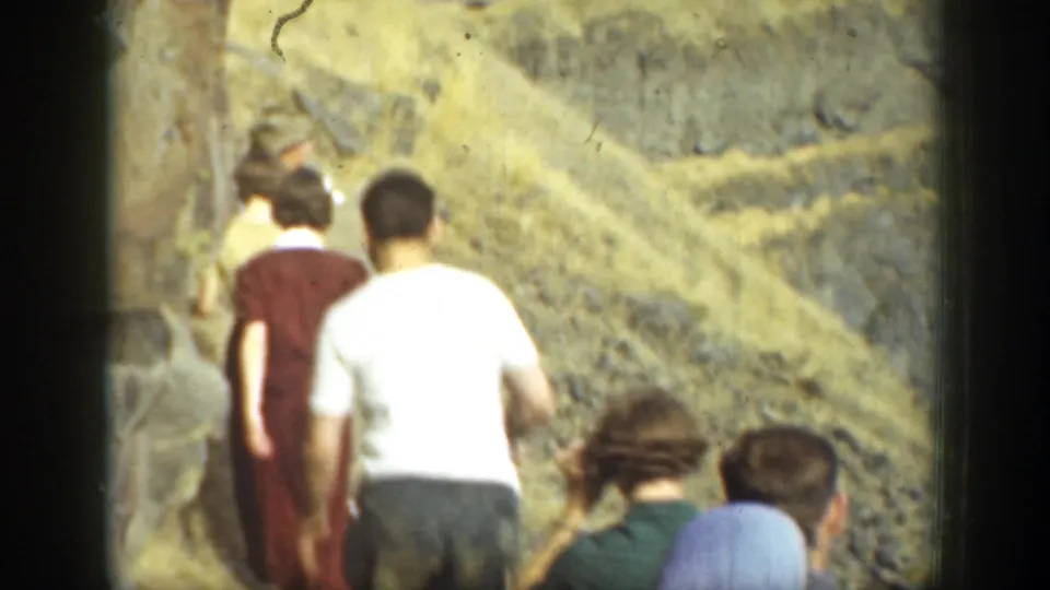 1937 California 8mm frame showing a small group hiking away from the camera on a rugged, rocky trail.