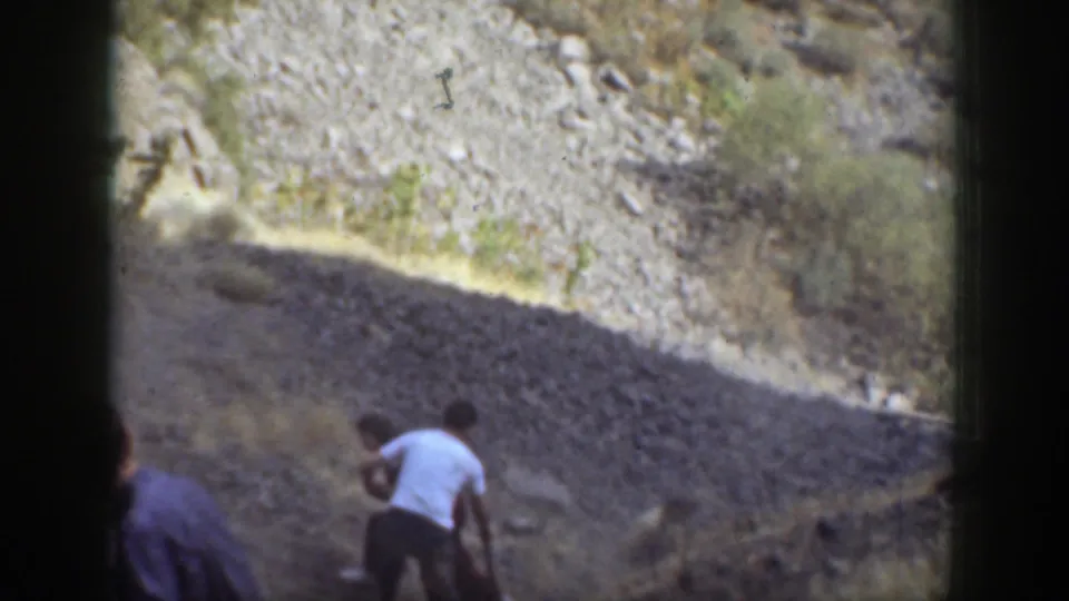 The final frame shows adults on the California hillside still focused on the apparent fallen person in the rocky terrain.