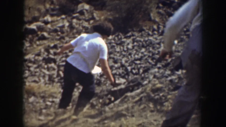 In 1937 California home-movie footage, a person in a white shirt carefully steps down a rocky slope.