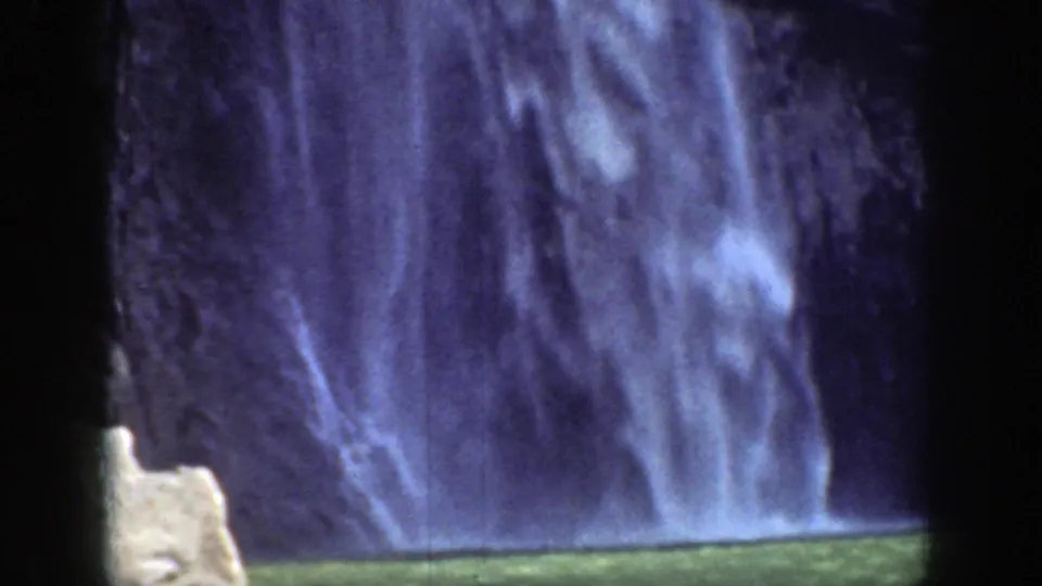 1937 California 8mm view of the lower waterfall, with blurred spray descending toward a green pool at the cliff base.