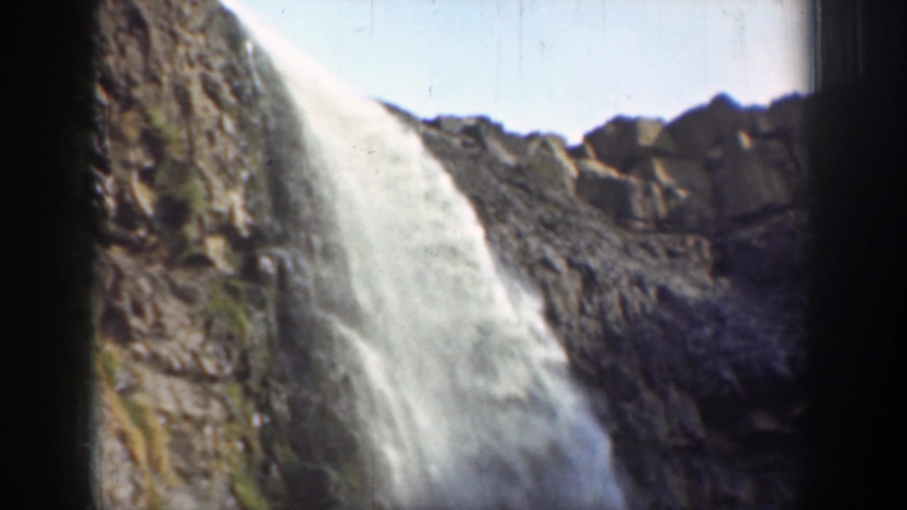 Waterfall dropping over rugged rocks with dark film borders.