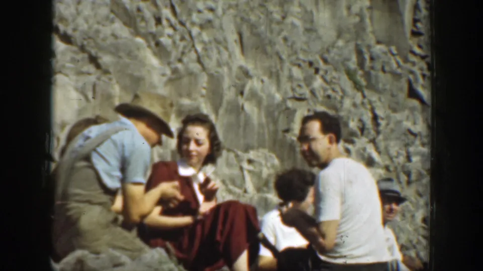 A small group of adults sits and talks below a rugged cliff face in 1937 California 8mm home-movie footage.