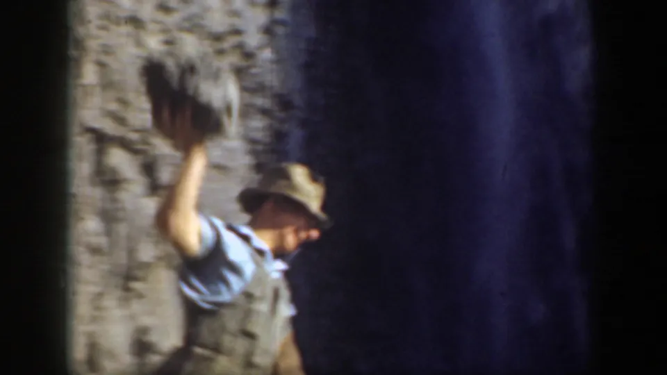 The man stands by the rugged California slope with his arm raised, preparing to throw or release the rock.