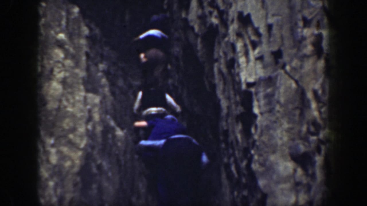 A man higher on the rock face while another follows below.