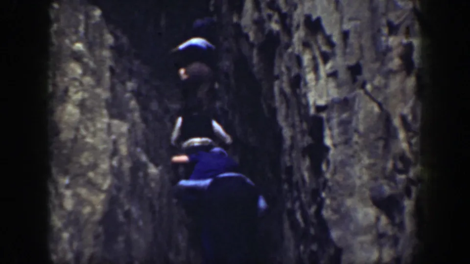 One climber reaches higher on a rugged California rock wall as another man follows below.
