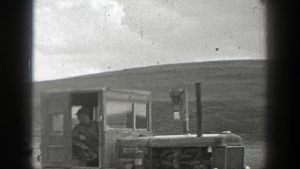 A farmer or operator is visible inside the cab of a tracked tractor during 1937 California field work, seen in grainy black-and-white 8mm footage.