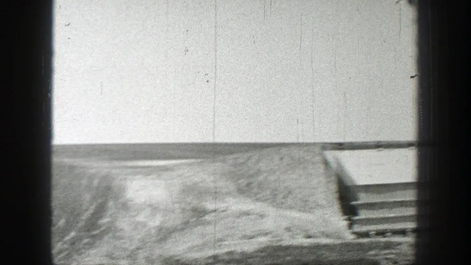 1937 California frame with open ground and horizon, while part of a low shelter-like structure remains visible on the right edge.