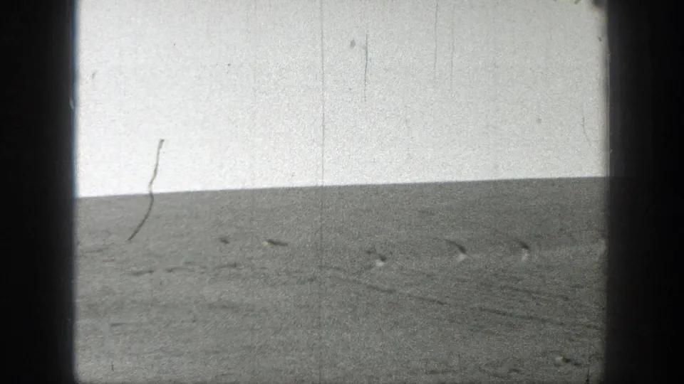 1937 California 8mm frame showing an empty grassy rise under a bright pale sky, bordered by dark film-gate edges.