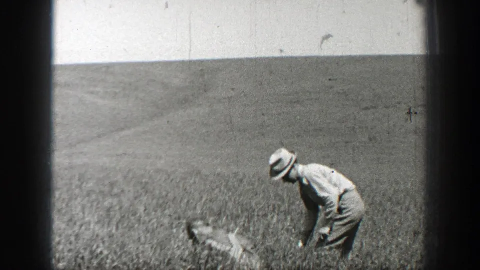 The man in a hat bends forward in the California field, appearing to tend or plant crops in the final sampled frame.
