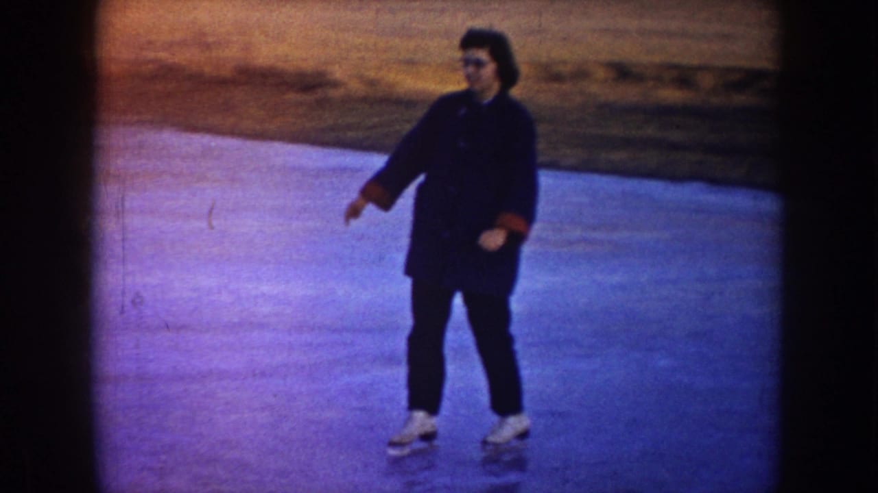 Adult skater in a dark coat gliding on outdoor ice.