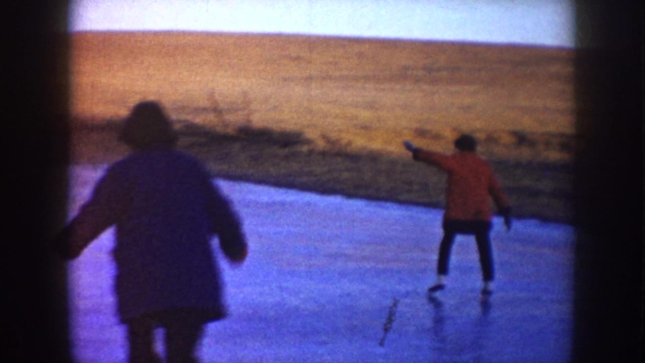 A home-movie frame shows two adults skating on a frozen pond, one closer to camera and one in a red jacket farther out.