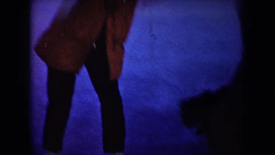 A red-jacketed child or small figure bends on the frozen surface in this grainy 1953 North Dakota winter home movie frame.