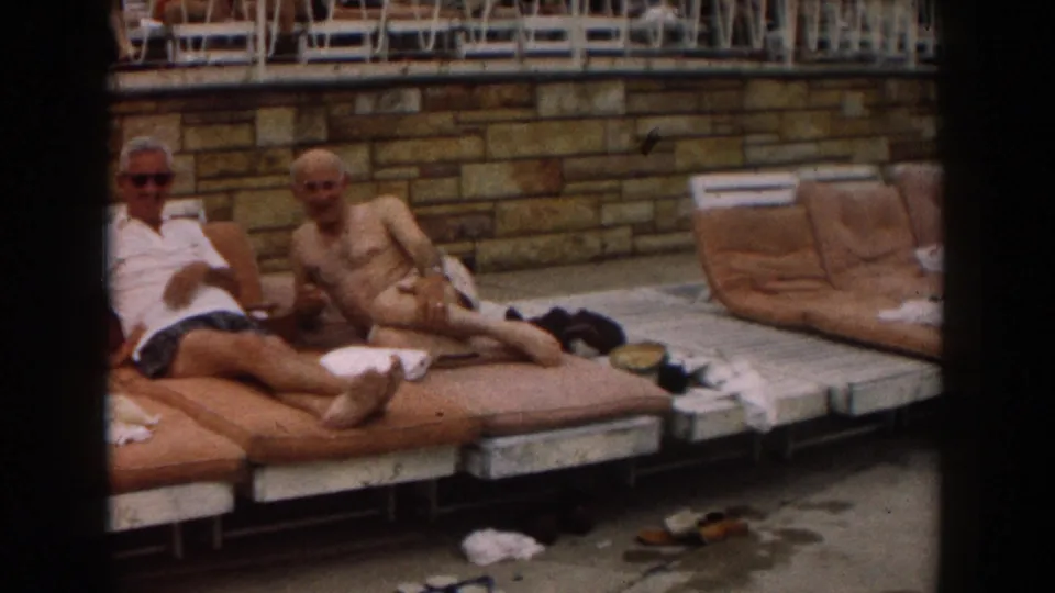 Two older men relax on cushioned poolside loungers in Los Angeles, 1961, with towels and sandals nearby.