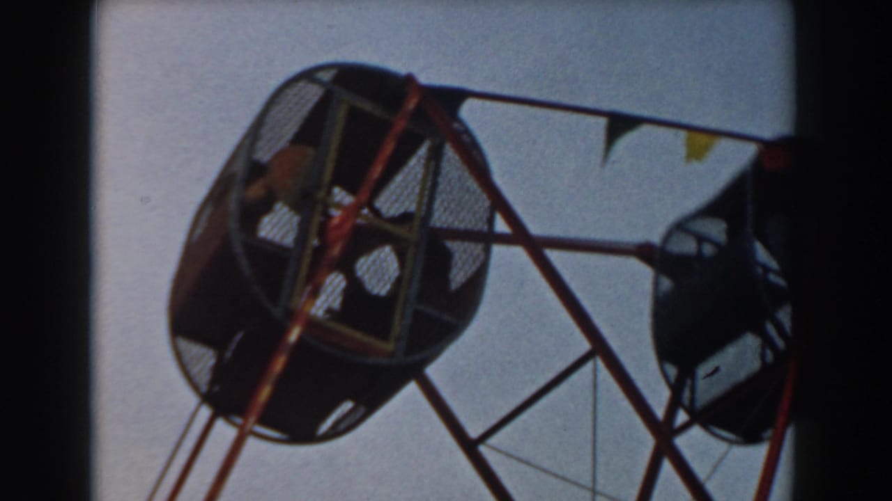 Ferris wheel gondolas and red support bars with small pennant flags against the sky.