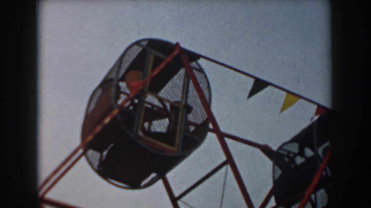 Low-angle view of a round mesh amusement ride cage with children inside.