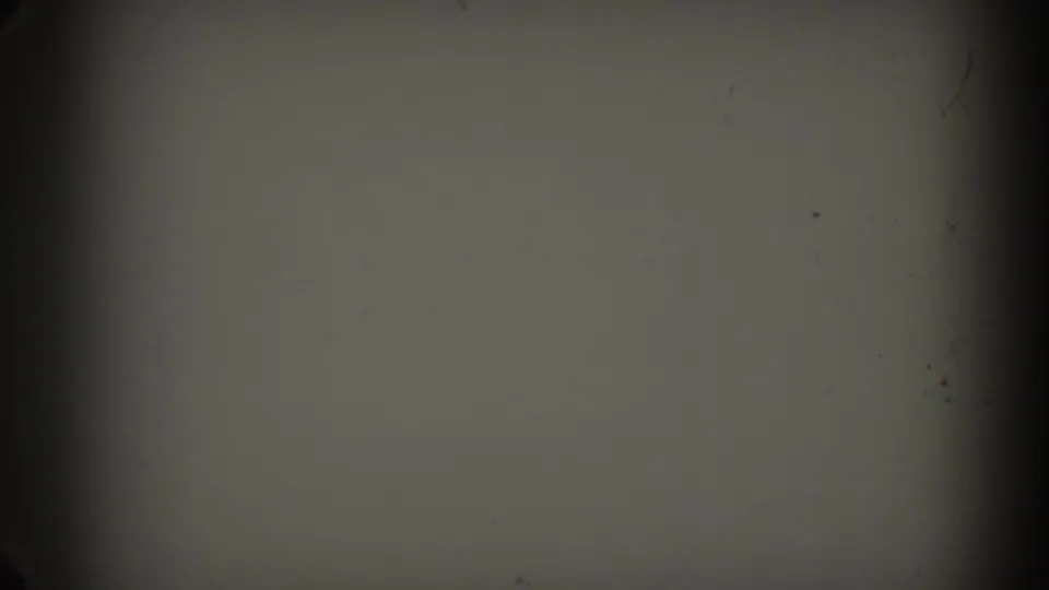 Opening 8mm frame with a largely blank pale area, dark film edge, and visible dust or grain before the people appear.