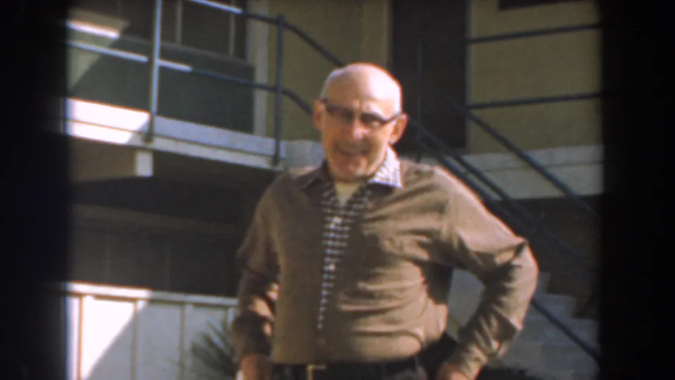 Near the end of the clip, the man smiles close to the camera outside the Los Angeles building, with stairs and railing behind him.