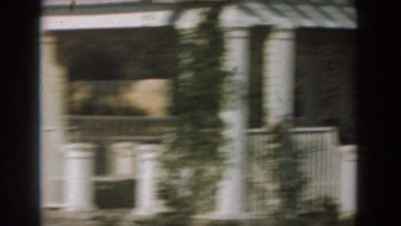 White columned porch or pavilion with railings, trees, and dark film-edge bands.