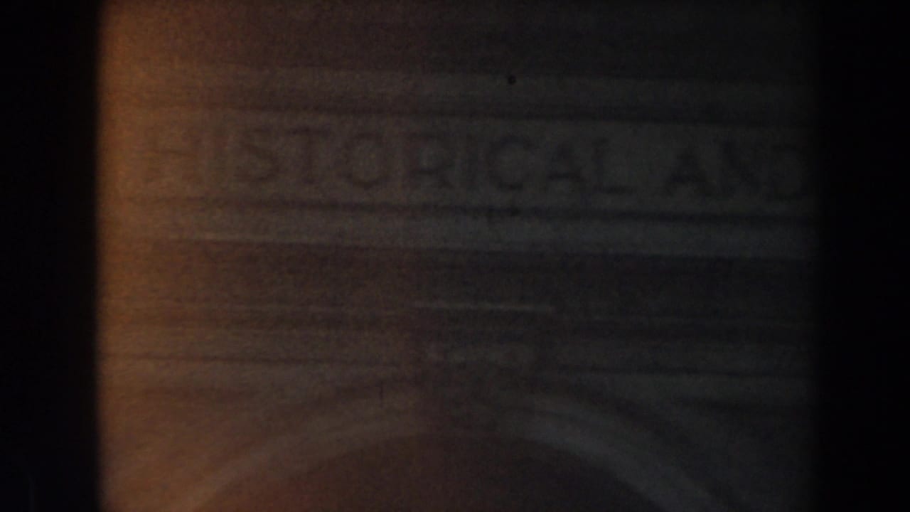 Dim stone building entrance with faint carved lettering above a doorway.