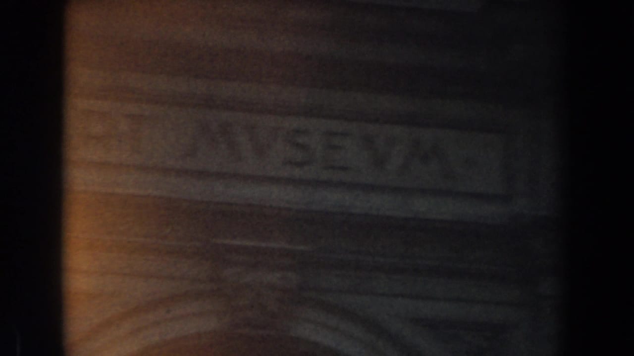 Low-light 8mm frame of a formal stone doorway area with partially visible lettering, building unidentified.
