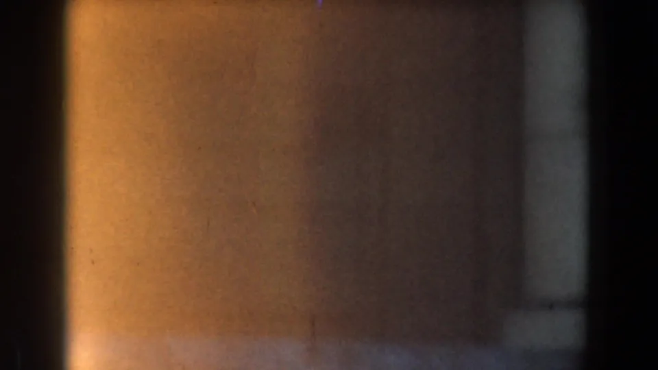 Soft 8mm frame with warm exposure at left and a blurred stone wall or column edge near the building entrance.