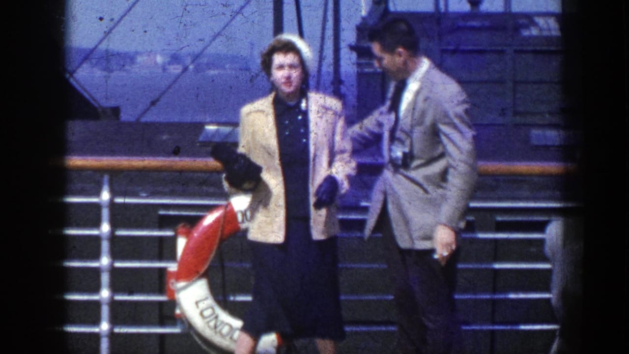 1948 New York-linked home-movie frame of two adults on a ship deck beside railings and a red-and-white life ring.
