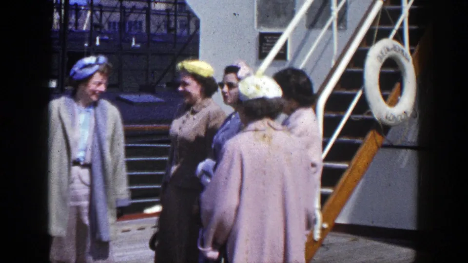 Women in period coats and hats gather on an outdoor ship deck near a stairway and life ring, supported as 1948 footage.