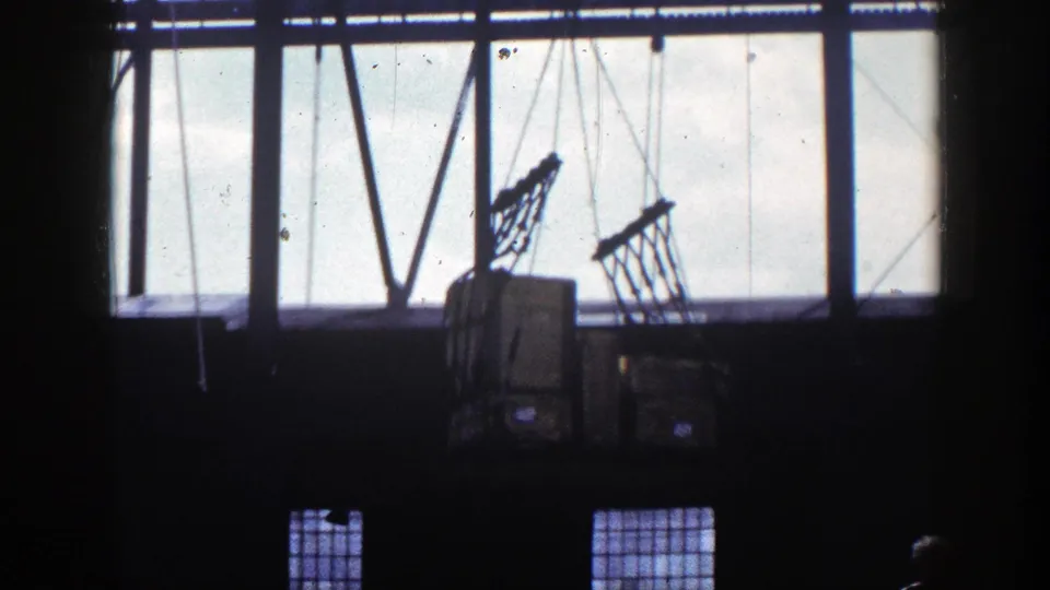 1948 New York warehouse frame with crane cables, netted cargo, box shapes, and high-contrast window silhouettes.
