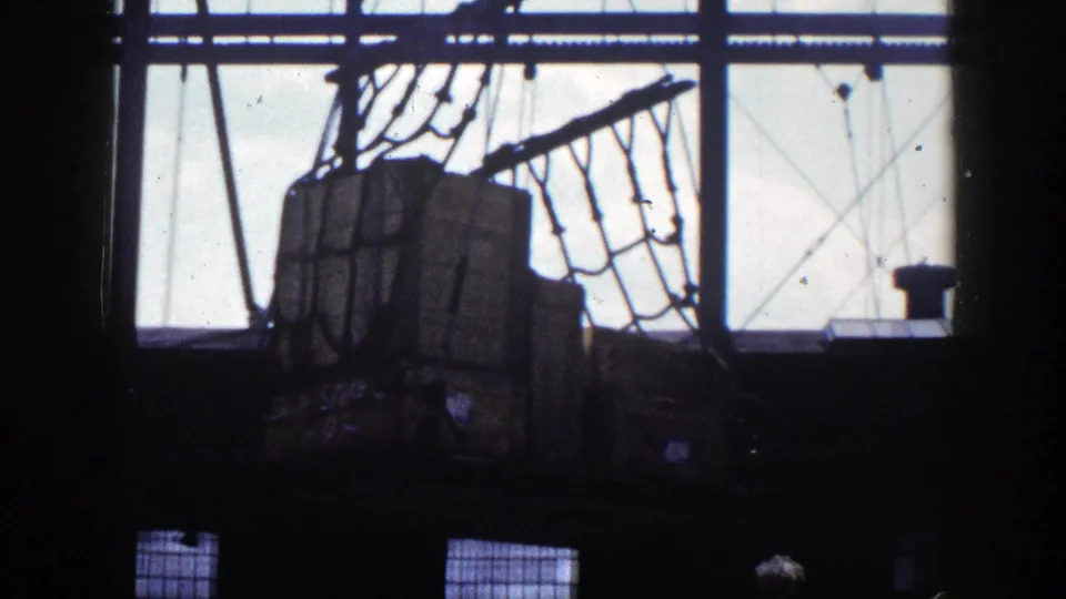 1948 New York dock view of wooden crates held in a rope cargo net against bright window openings and dark interior framing.