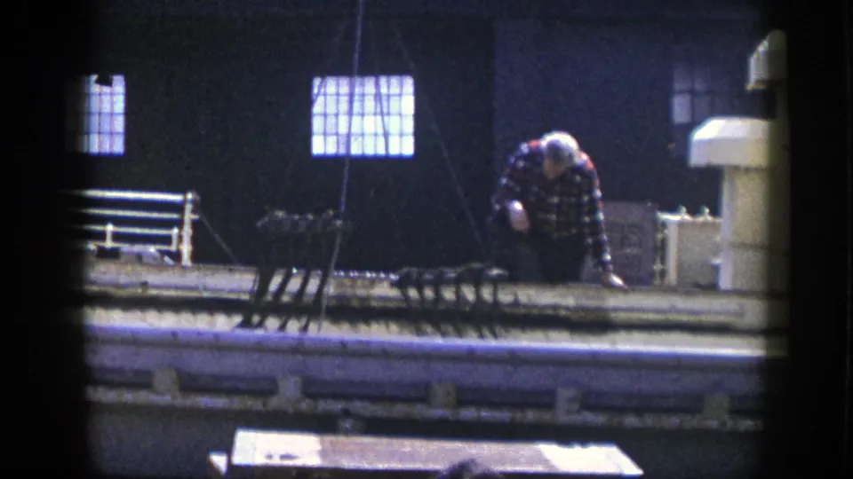 1948 New York factory scene with a worker adjusting equipment near pipes, machinery, and bright high windows.