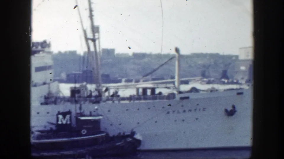 1948 New York harbor footage showing the Atlantic passenger ship with a tugboat at its side and shoreline beyond.