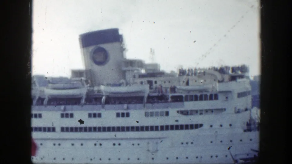 Soft 8mm frame of a 1948 New York ocean liner at port, showing the funnel, porthole rows, deck railings, and passengers.