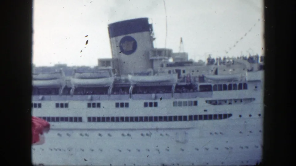 1948 New York harbor home-movie frame showing a white ocean liner at the pier with passengers on deck and visible film wear.
