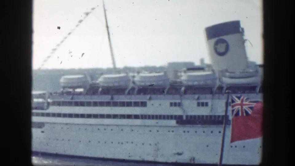 New York 1948 harbor footage frames the white liner's decks and funnel beside a foreground red ensign flag.