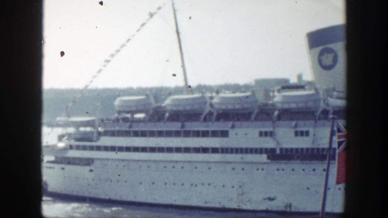 1948 New York harbor footage appears to show a white ocean liner with lifeboats, viewed through dark framing bars from a nearby vantage point.