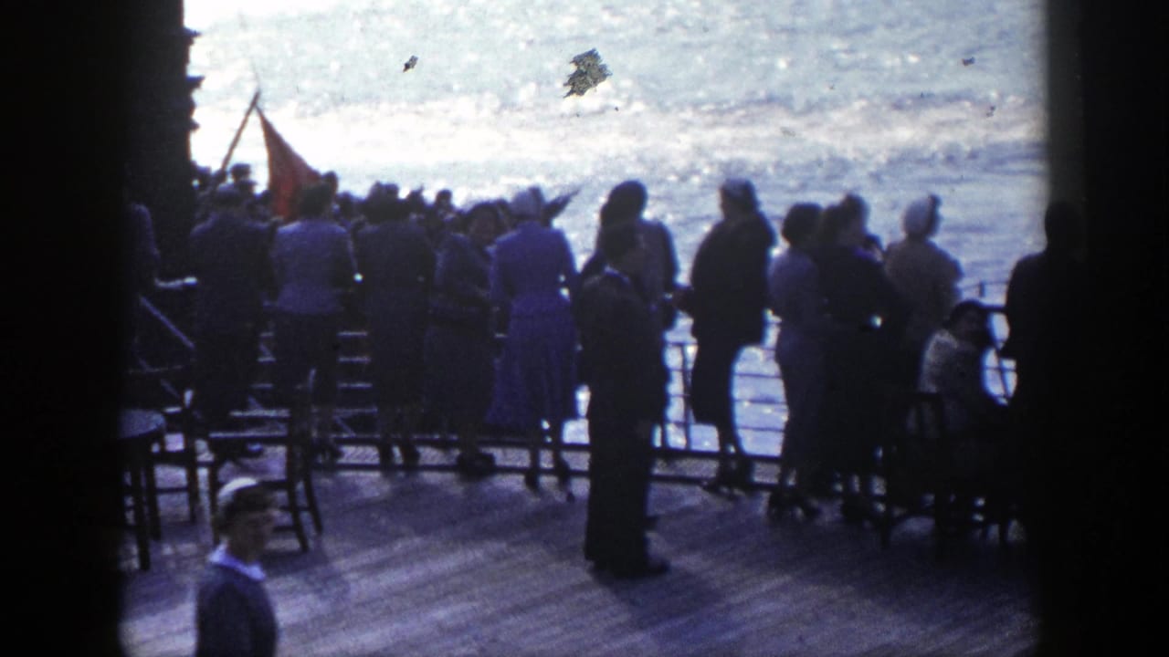 In 1948 New York home-movie footage, passengers in period clothing stand on a ship deck watching activity on the water.