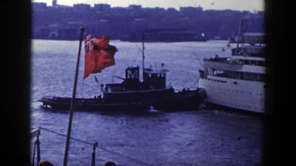 The red flag, tugboat, passenger liner, and hazy skyline remain visible in this 1948 New York harbor view.